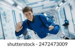 Portrait of Courageous Caucasian Male Astronaut on Board a Spacecraft, Floating in Zero Gravity and Smiling At The Camera, Waving. Space Travel, Solar System Exploration and Colonization Concept