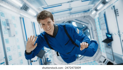Portrait of Courageous Caucasian Male Astronaut on Board a Spacecraft, Floating in Zero Gravity and Smiling At The Camera, Waving. Space Travel, Solar System Exploration and Colonization Concept - Powered by Shutterstock