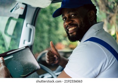 Portrait of courier black man in the truck smiling to camera while using tablet find house location of customer, Optimistic man worker with delivery occupation. - Powered by Shutterstock