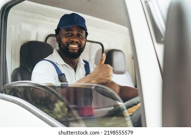 Portrait of courier black man in the truck thumb up and smiling to camera while sitting in driver seat, Optimistic man worker with delivery occupation. - Shutterstock ID 2198555579