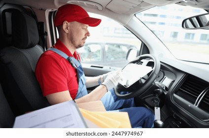 Portrait of courier driver using digital tablet sitting in van. Delivery service and delivery concept