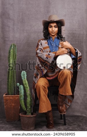 Portrait, cowgirl or woman with instrument for music in studio and cool fashion or clothing on grey background. Native American person, western and model with plants, boho style and banjo for a song