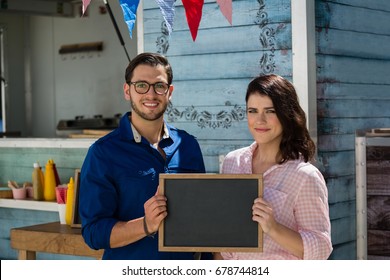 Portrait of coworkers holding writing slate while standing by food truck - Powered by Shutterstock