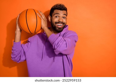 Portrait of crazy funky person hands hold basketball beaming smile empty space isolated on orange color background - Powered by Shutterstock