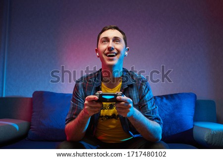 Portrait of crazy playful Gamer , boy enjoying Playing Video Games indoors sitting on the sofa, holding Console Gamepad in hands. Resting At Home, have a great Weekend