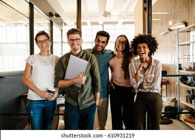 Portrait of creative business team standing together and laughing. Multiracial business people together at startup. - Shutterstock ID 610931219