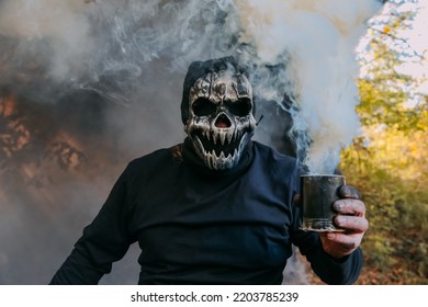  A Portrait Of A Creepy Scary Man In Skeleton Mask. Monster Holding Smoke Bomb In His Hand. Halloween. Horror Film.