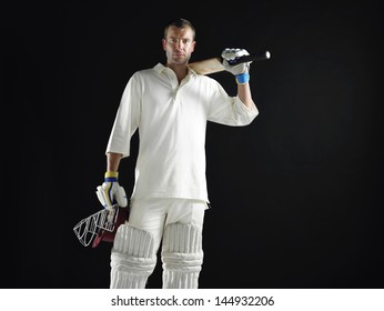 Portrait of a cricket player holding bat and helmet against black background - Powered by Shutterstock