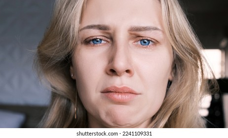 Portrait of crying grieving woman of 30 years. Grimace of sadness with tears in her eyes and crooked chin of blonde woman looking at camera. Emotional swing, unstable psyche, mental problems