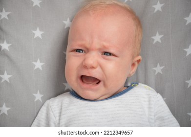 Portrait Of Crying Newborn Baby, Close-up. Cut Child With Blue Eyes. Face Expression.