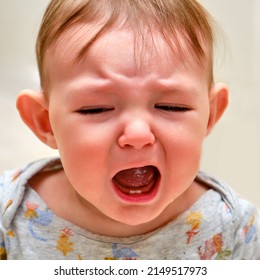 Portrait of a crying toddler baby boy. The face of an unhappy child with tears in his eyes, close-up