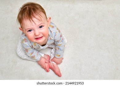 Portrait of a crying toddler boy sitting on the floor. Face of an unhappy child with tears in his eyes, copy space