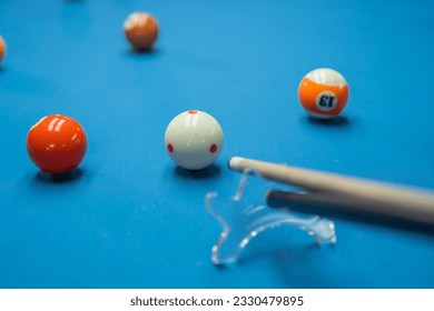 portrait of the cue stick poking the white ball helped by the bridge at the billiard game
