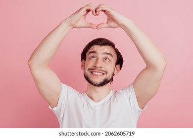 Portrait Of Curious Charming Guy Show Heart Symbol Look Up On Pink Background