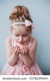 Portrait Of Cute 5 Years Old Girl Blowing Gold Glitter. Fairy Christmas Concept.