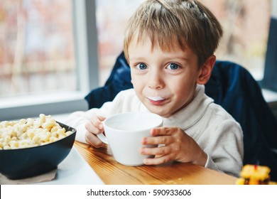 Portrait Of Cute Adorable Caucasian Child Kid Boy Drinking Milk From White Cup Eating Breakfast Lunch Early Morning, Everyday Lifestyle Candid Moments