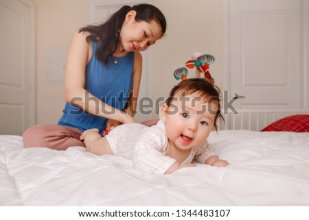 Portrait of cute adorable mixed race Asian mother with newborn baby doing massage and physical exercises. Early development and health care lifestyle concept