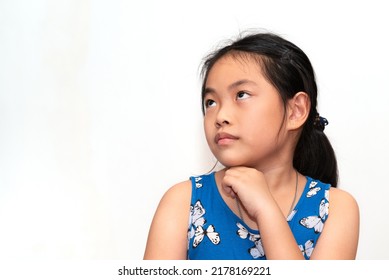 Portrait Of Cute Asian Child Girl Is Thinking, Looking At The Right Side And Slightly Up, One Hand At Chin, Black Long Hair, Asian Child Girl At 8-9 Years Old, Isolated Image On White Background.