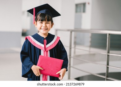 Portrait of a cute Asian graduated schoolgirl with graduation gown in school - Powered by Shutterstock