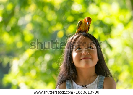 Portrait of cute  asian little girl enjoy  with pet parakeet parrot on summer outdoor , Lifestyle  education Concept