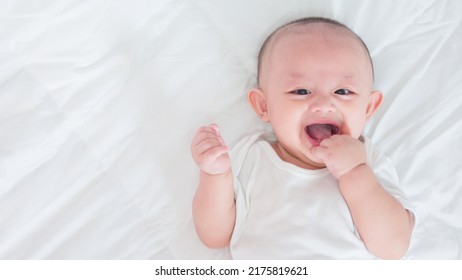 Portrait Of Cute Asian Newborn Baby Lying Play On White Bed Look At Camera With Laughing Smile Happy Face. Innocent Little New Infant Adorable. Parenthood And Mother Day Concept.