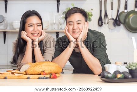 Portrait cute Asian young adult couple lover helping together, cooking in cozy home kitchen in morning, preparing breakfast meal, smiling each other with happiness. Lifestyle, Leisure, Love concept
