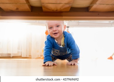 Portrait Of Cute Baby Boy Crawling And Looking Under The Bed