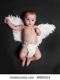 Portrait Of A Cute Baby Boy Wearing Fake Angel Wings, Black Background