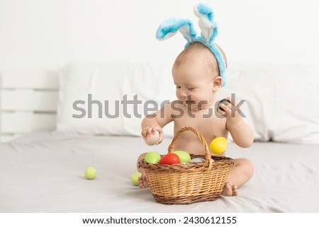 Portrait of a cute baby dressed in Easter bunny ears with a basket full of eggs