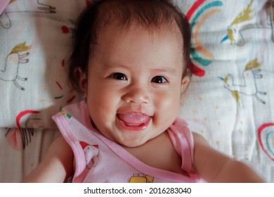 Portrait Of A Cute Baby Girl 6 Months Old Baby Lying Down On A Bed, Top View, Adorable Asian Little Girl On Bed And Looking At The Camera