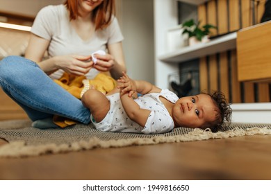 Portrait Of Cute Baby Girl, Laying Down, Mom Sitting Next To Her.