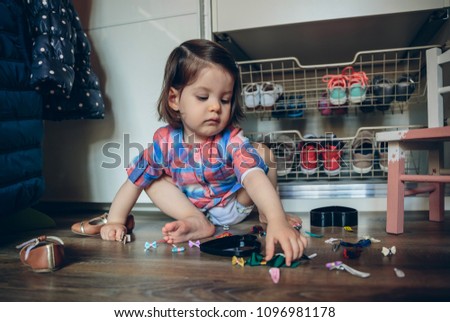 Baby girl playing with hair clips sitting in the floor