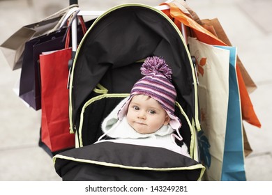 Portrait Of Cute Baby In Stroller Hung With Shopping Bags