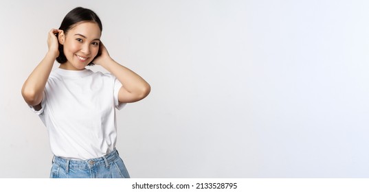 Portrait Of Cute, Beautiful Asian Woman Touching Her New Short Haircut, Showing Hairstyle, Smiling Happy At Camera, Standing Over White Background