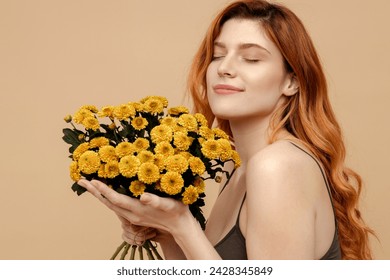 Portrait cute beautiful red haired woman with eyes closed holding bunch of spring flowers isolated on beige background. Natural beauty, International woman's Day - Powered by Shutterstock