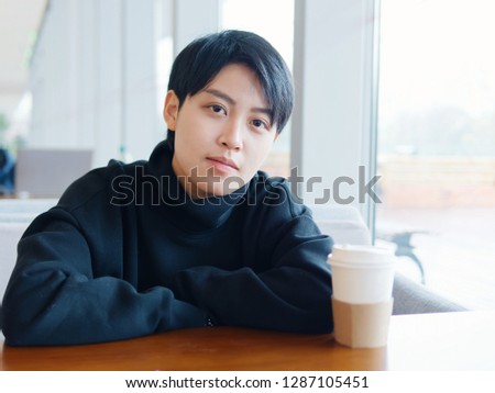 Portrait of cute beautiful young lesbian with short haircut and trendy boyish clothes sitting in coffee shop, friendly Chinese gay girl.