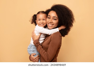 Portrait of cute black girl and her mother hugging and smiling at camera, beige background, healthy united family, mother daughter bonding concept - Powered by Shutterstock