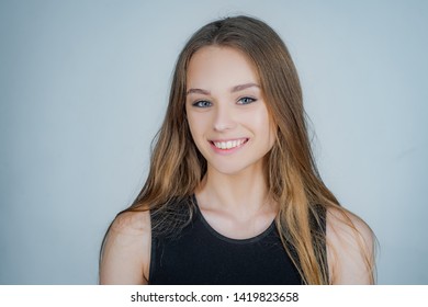 Portrait of a cute blonde girl standing on white background. Close up portrait of young cheerful beautiful girl with long hair in casual shirt smiling looking in camera with happy face expression