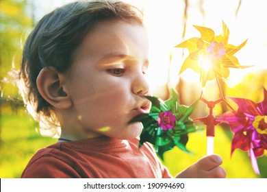 Portrait Of A Cute Boy Blowing Wind Wheel In Sunshine