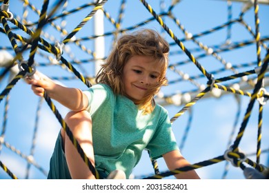 Portrait Of Cute Boy Child Doing Rock Climbing In The Playbackground. Little Kid Hanging On The Monkey Bar By His Hand To Exercise At Outdoor Playground.