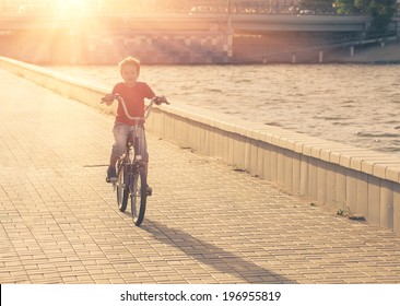 Portrait of a cute boy on bicycle. Young school boy on a bicycle backlit against sunlight, warm vintage color. - Powered by Shutterstock