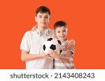 Portrait of cute brothers with soccer ball on color background