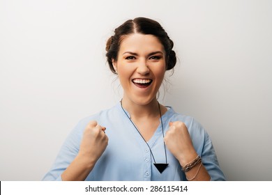 portrait of a cute brunette girl rejoices victory with clenched fists