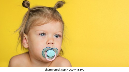 Portrait Of Cute Caucasian Child Kid Little Girl Of 2 Years With Pacifier In Mouth On Yellow Background With Copy Space