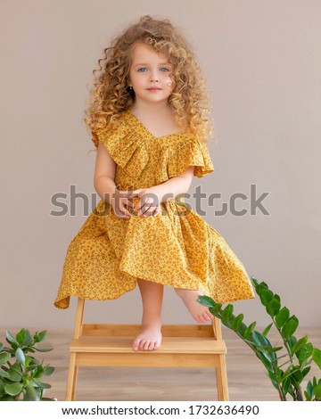 portrait of a cute curly beautiful girl blonde at home with plants