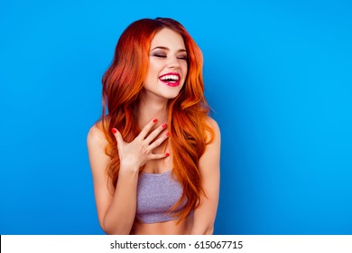 Portrait of cute excited  attractive girl with long ginger fair hair laughing while standing on blue background