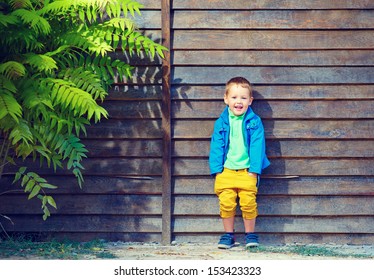 portrait of cute fashionable boy in front of wooden wall