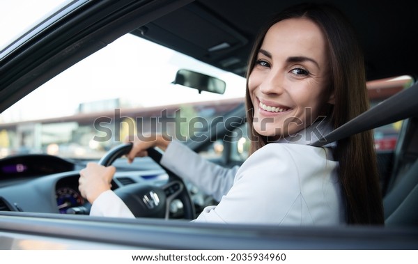 Portrait of cute female driver steering car with\
safety belt