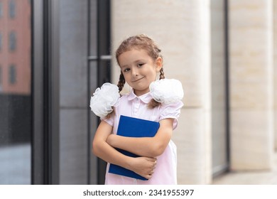 portrait cute funny smart schoolgirl with book. back to school. happy child, clever girl go to first grade.