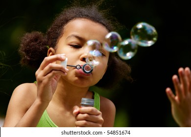Portrait of cute girl blowing soap bubbles